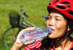 Young woman enjoying a bottle of water outdoors on a bike trip.